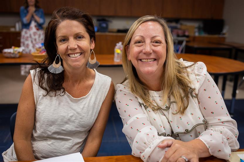 A PTO president smiles while sitting at a table with her school principal